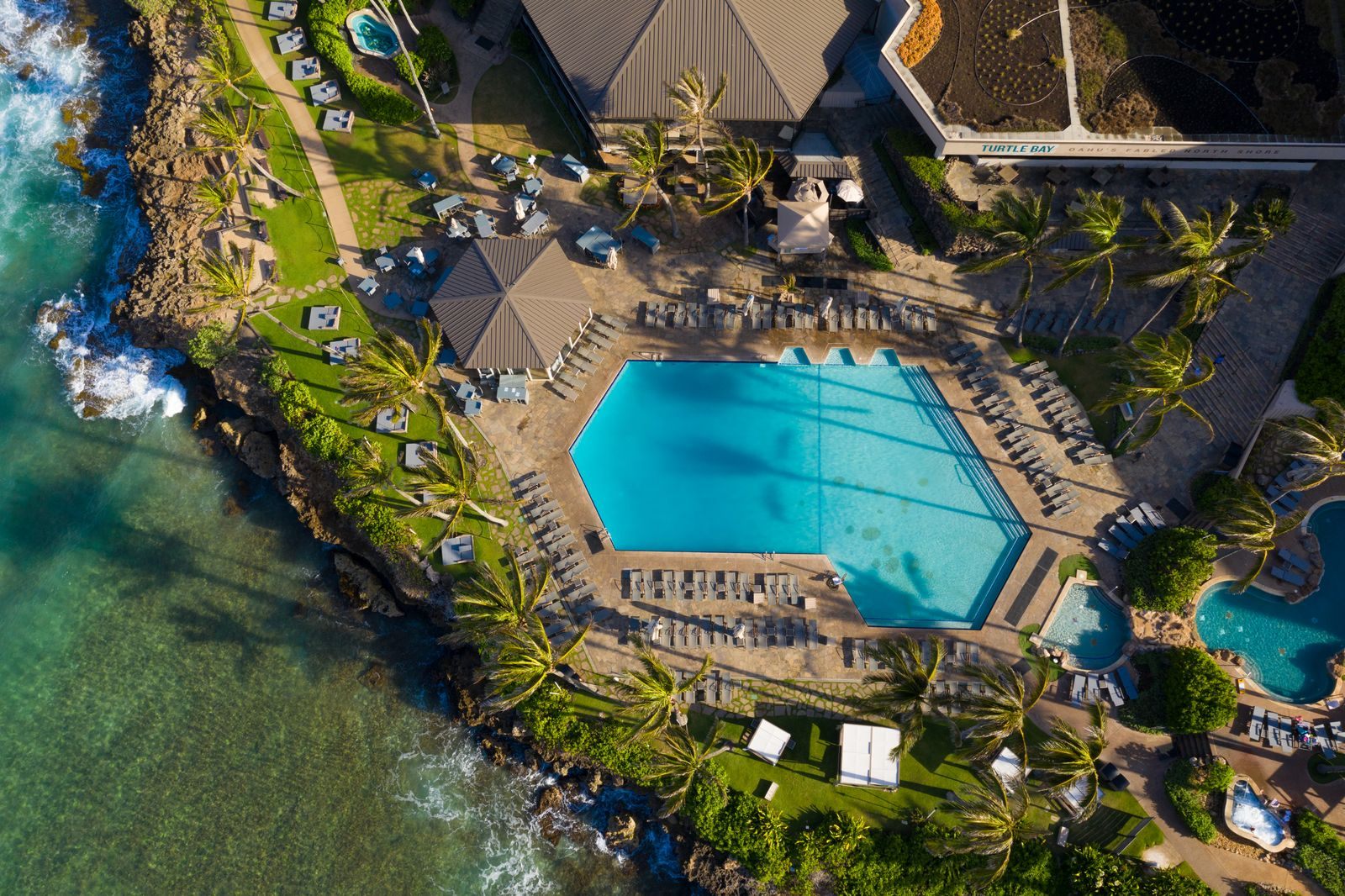 Aerial view of a resort pool on a rocky point on Oahu, a stay to add before or after a cruise