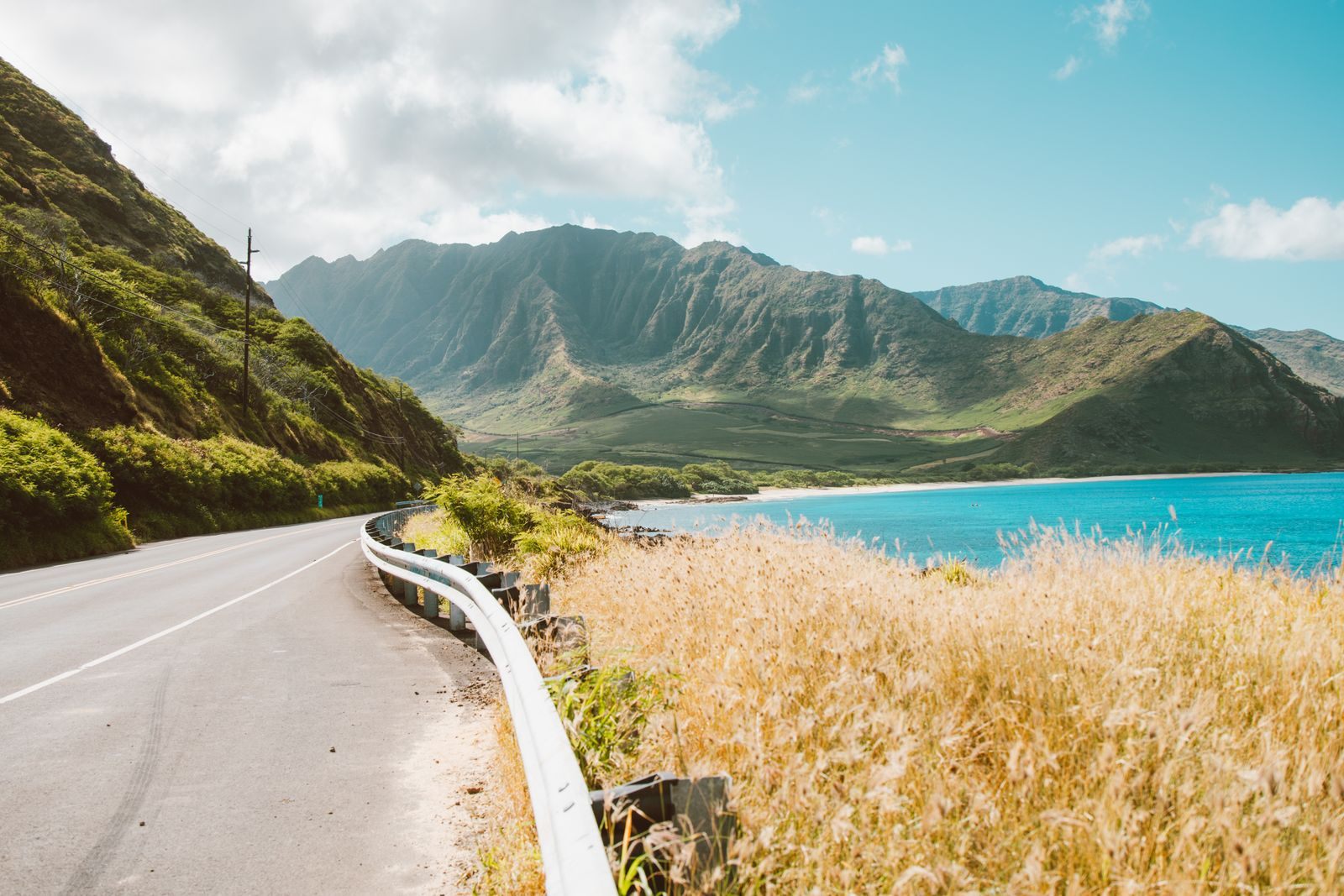 Coastal highway on Oahu winding between green mountains and turquoise water