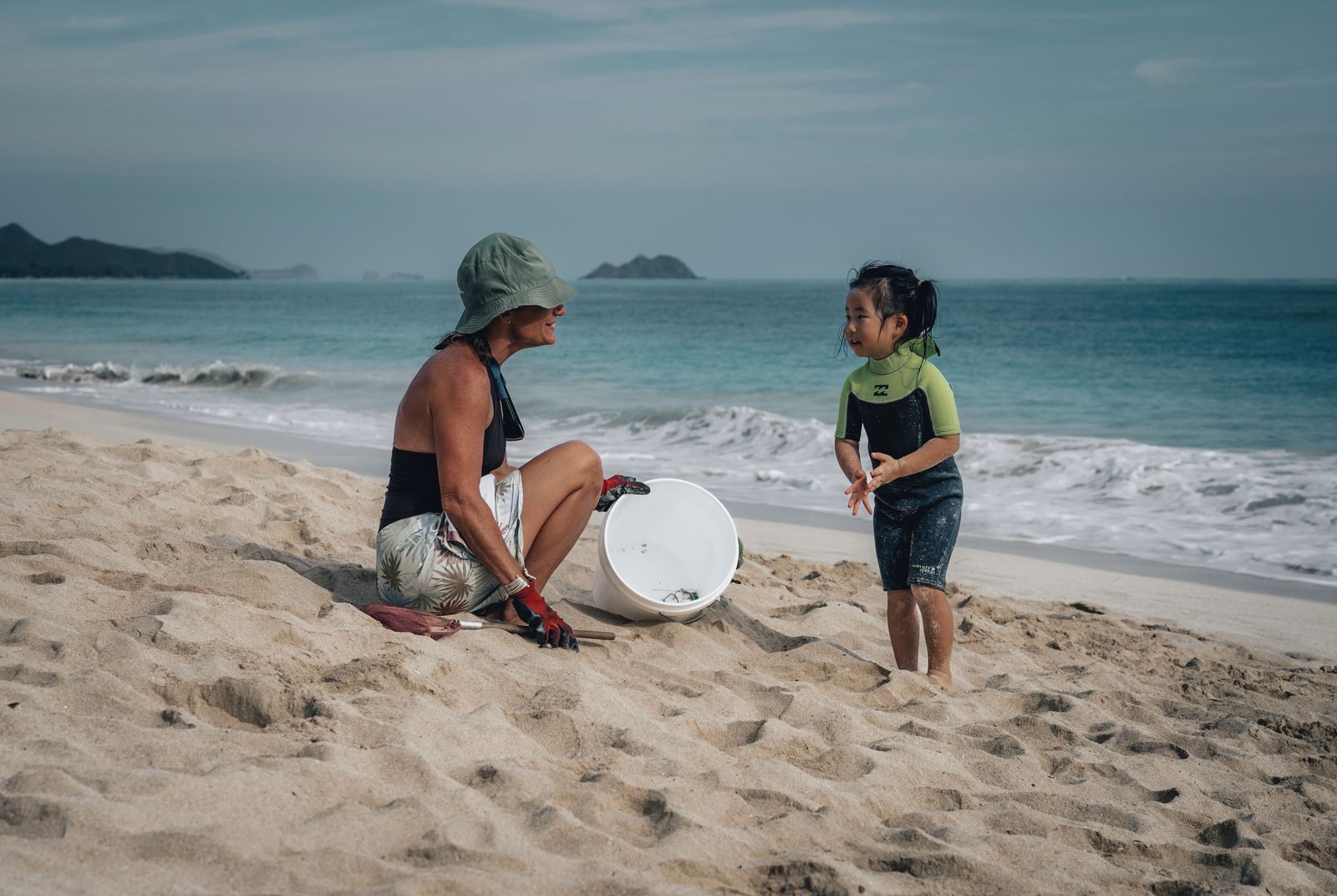 Mother and young daughter playing on a Hawaiian beach with offshore islets in the distance